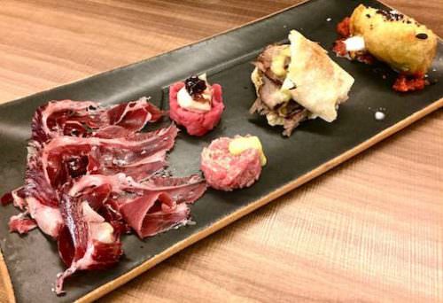 Prosciutto di spalla Joselito, due piccole tartare di pura razza piemontese (una con foie gras e confit di cipolle, l'altra alla ligure), succulento, memorabile Pastrami su crosta di pane e Fiori di zucchine con burrata e acciughe del mar Cantabrico)